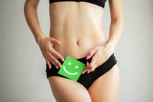 Woman holding paper with smile mark over her stomach. Health hygiene sexual education concept