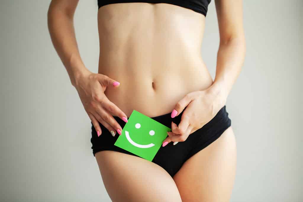 Woman holding paper with smile mark over her stomach. Health hygiene sexual education concept